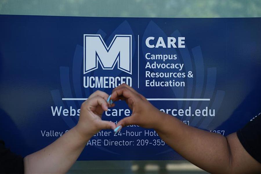 hands forming a heart in front of a uc merced care banner